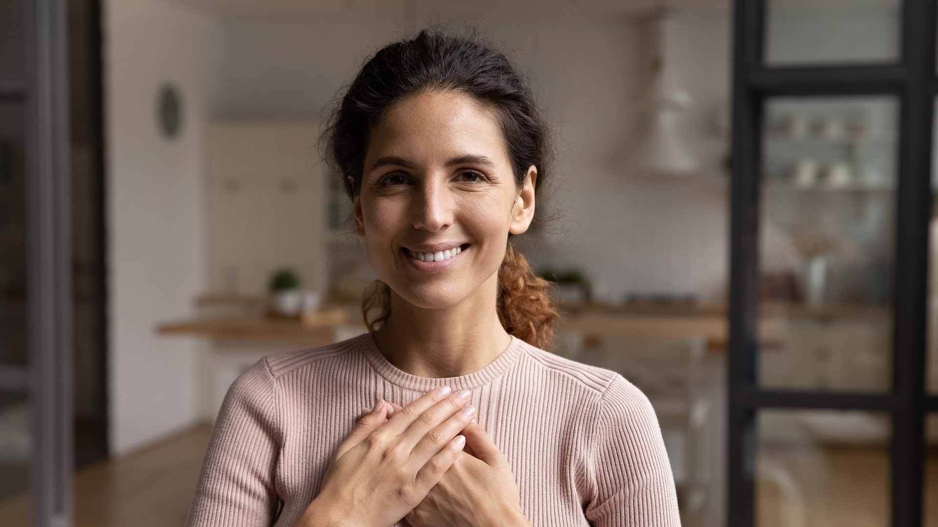 Aktiv werden - Förderverein Lächelnde Frau legt dankbar die Hände aufs Herz – Symbolbild für Mitgefühl, Unterstützung und Engagement des Fördervereins Malteser-Johanniter-Johanneshaus e.V. zur Verbesserung der Lebensqualität psychisch erkrankter Menschen.